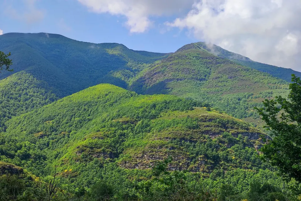 Green mountain ridges under a cloudy sky seen from a climb