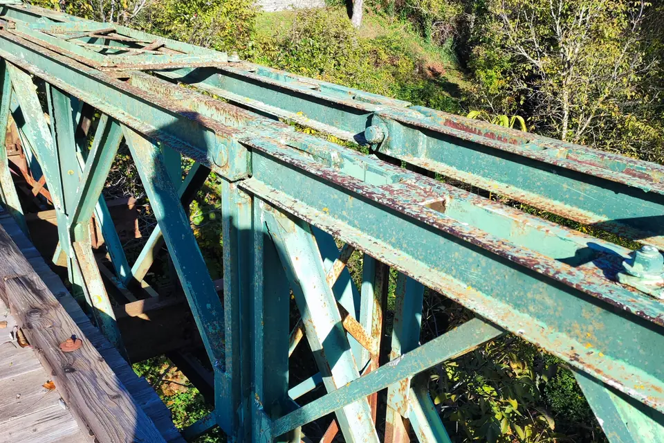 Green steel girders of an old railway bridge crossed by bike