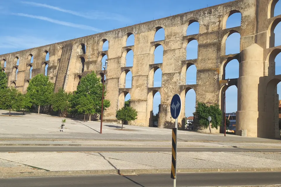 Long stone aqueduct with rows of arches seen from the road