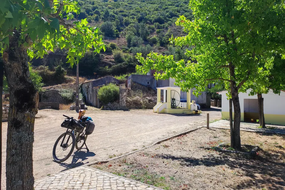 Bike parked in a shaded village street between houses and trees
