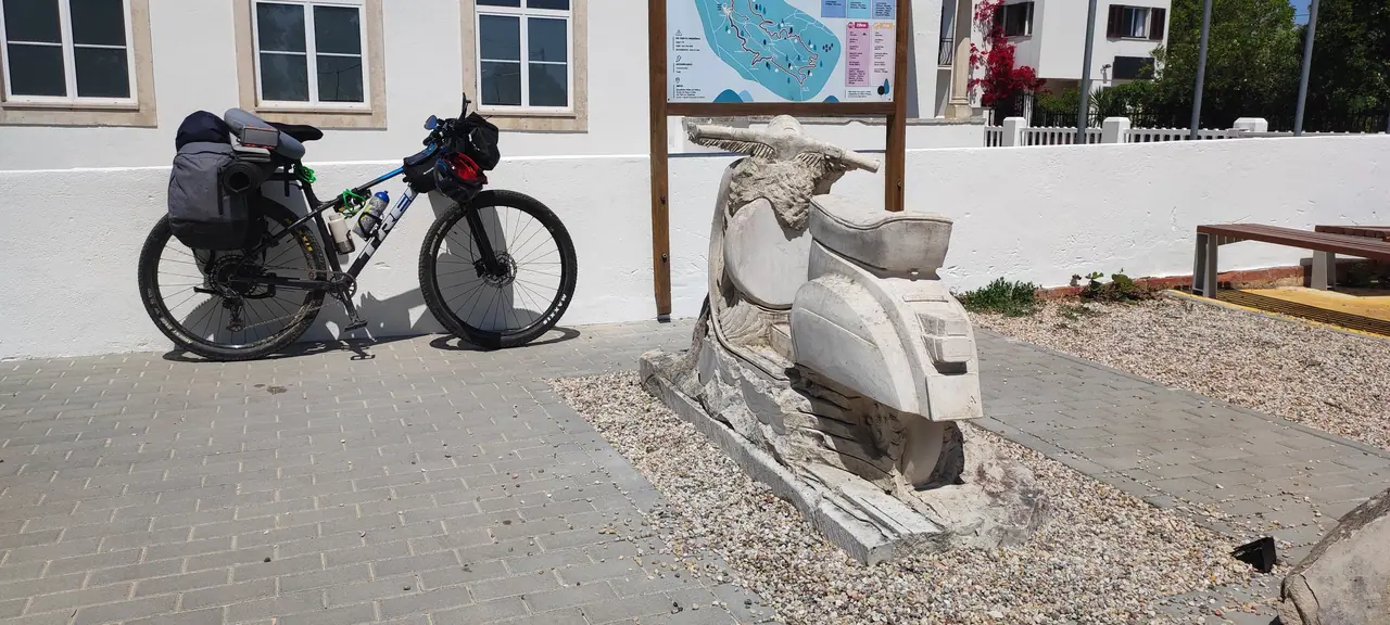 Two loaded touring bicycles stopped in a sunlit stone-paved Salento village