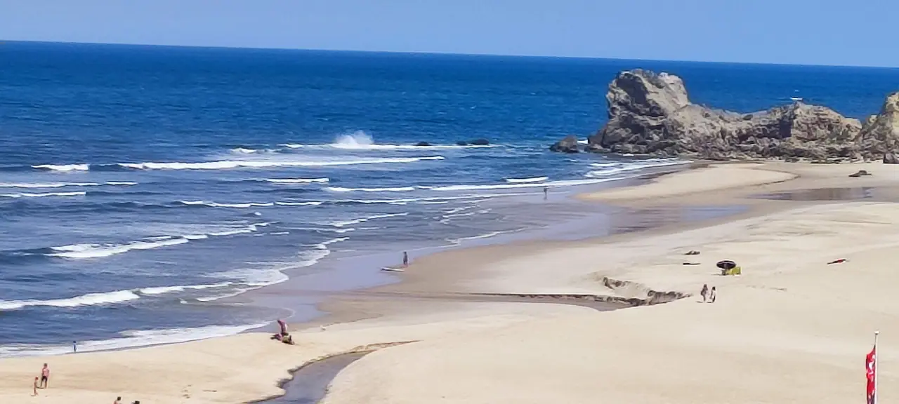 Wide sandy bay, clear blue Adriatic Sea and a rocky sea stack off the Salento coast