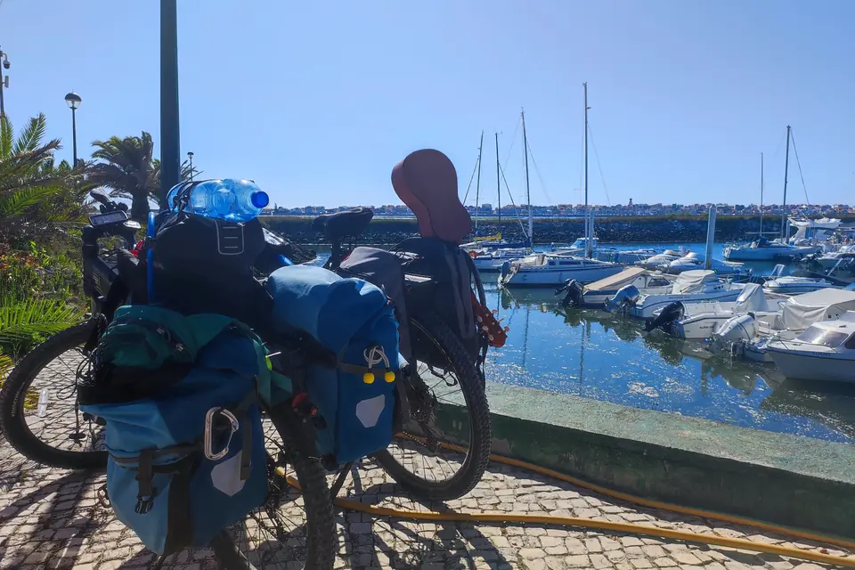 Bici da viaggio cariche in sosta in un porticciolo pieno di barche a vela