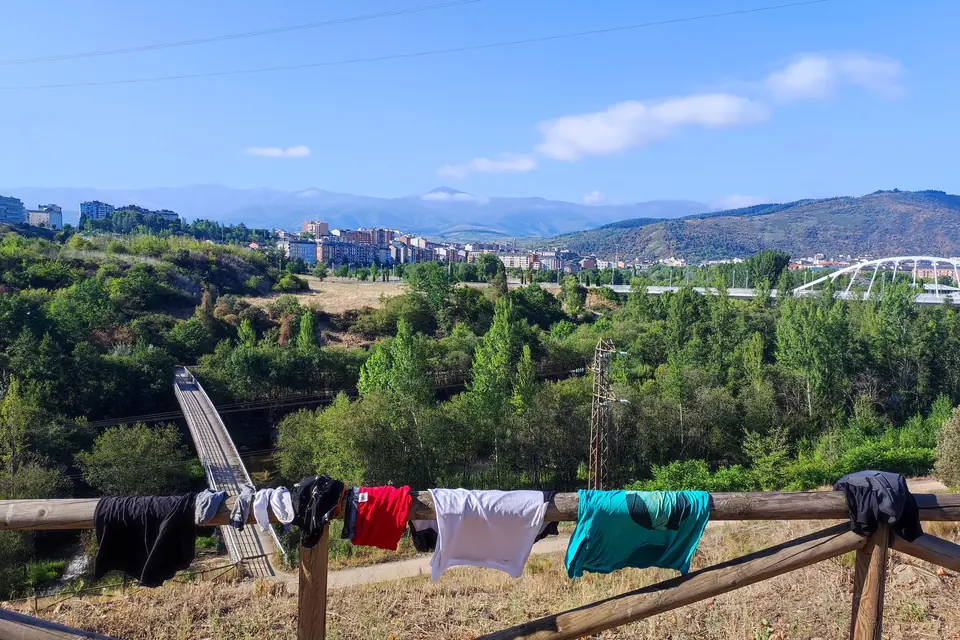 Cycling kit drying on a fence with a green valley behind