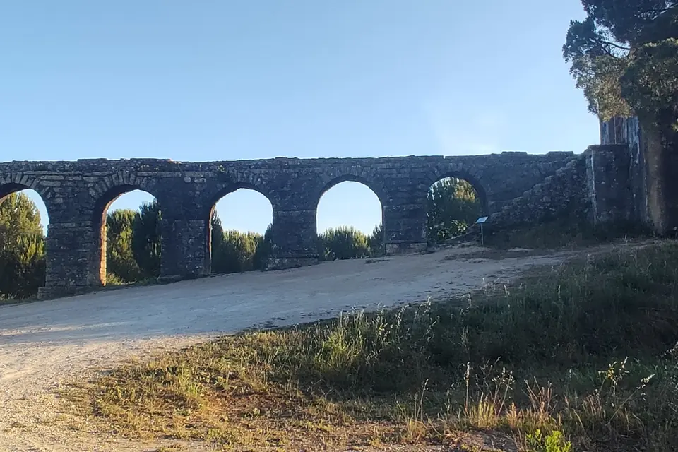 Arches of a ruined aqueduct beside a quiet country road