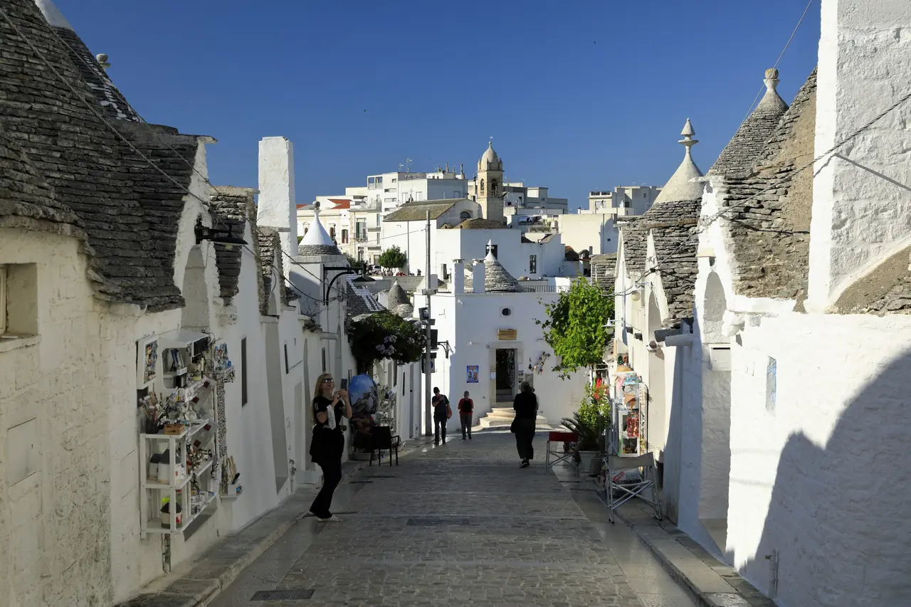 A street of cone-roofed trulli climbing through the Rione Monti district of Alberobello